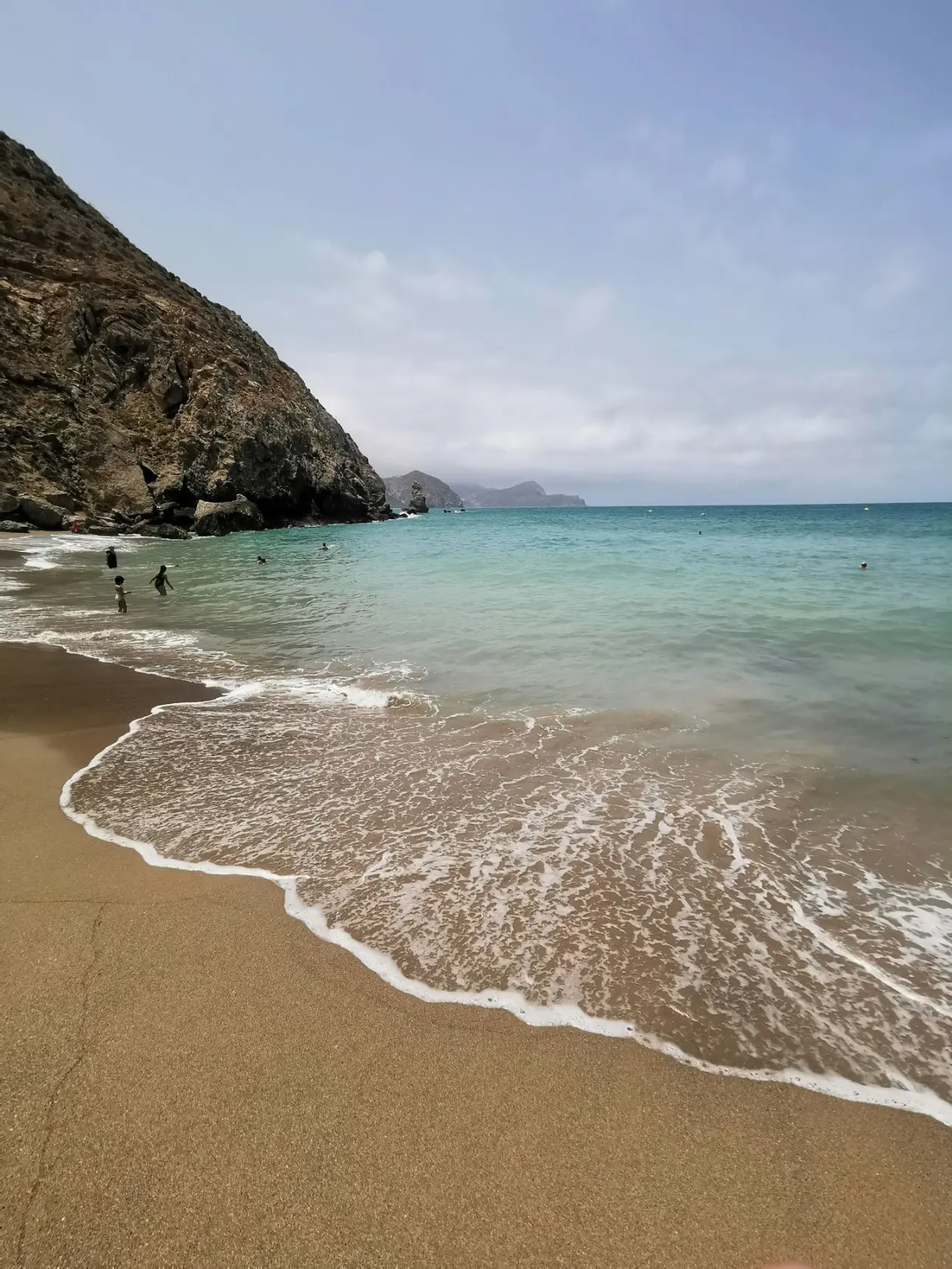 brown sand beach with brown rock formation